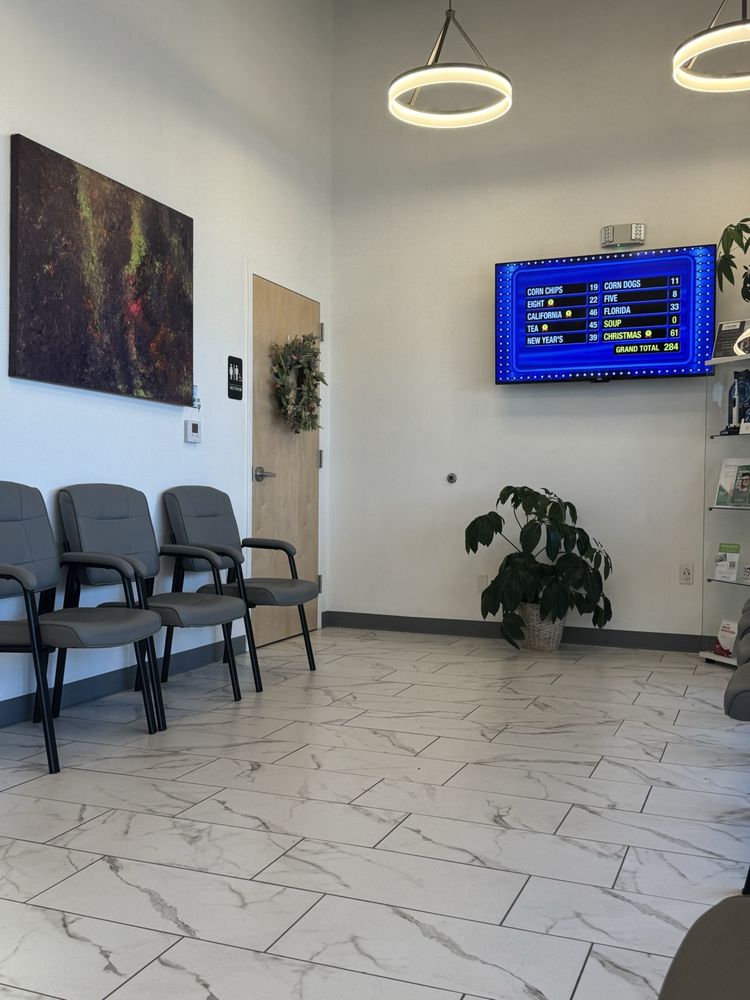 Waiting room with chairs and a TV at Davis Dental
