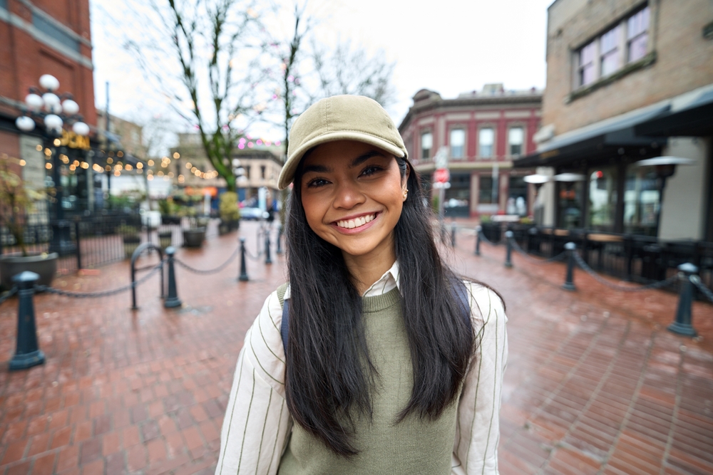 Smiling young woman in a cap on a city street